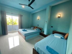 ein Schlafzimmer mit zwei Betten und einem Deckenventilator in der Unterkunft The Shore Residence in Hikkaduwa
