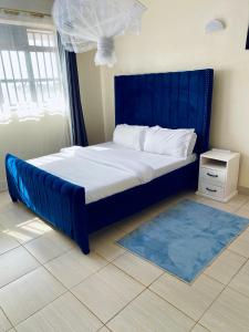 a bed with a blue headboard in a bedroom at Exquisite Modern suite 1bedroom in Busia