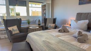 ein Schlafzimmer mit einem Bett und zwei Stühlen und einem Fenster in der Unterkunft Seedeich Meehrblick Alte Liebe in Cuxhaven