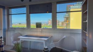 ein Raum mit Tisch und Stühlen und Fenstern in der Unterkunft Seedeich Meehrblick Alte Liebe in Cuxhaven