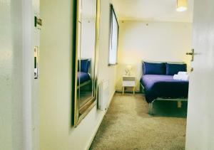 une chambre avec un lit bleu et un miroir dans l'établissement Comfy 3BR Flat on Quiet Street in Wollaton, à Nottingham