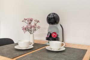 a coffee machine sitting on a table with two cups at Saulės apartamentai su vaizdu į Kušių marias in Neringa