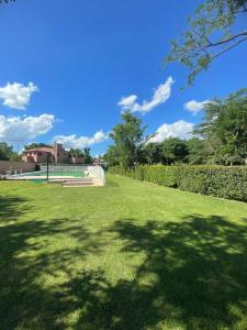 a park with green grass and a shadow of a tree at La Charito in Villa Cura Brochero