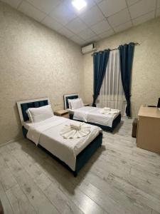 - 2 lits dans une chambre dotée de rideaux bleus dans l'établissement Green Hotel, à Tachkent