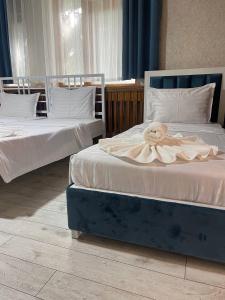 Deux lits avec des draps blancs et une fleur sur eux dans l'établissement Green Hotel, à Tachkent