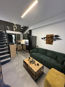 een woonkamer met een groene bank en een tafel bij TrikalaBnB - Prime Loft 2 in Tríkala