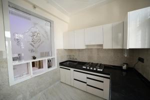 Una cocina con gabinetes blancos y una encimera negra. en The Laxmi Royale Villa, en Jaipur