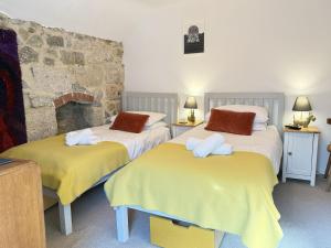 two twin beds in a room with a stone wall at Sixpence Cottage, a few steps from the harbour! in St Ives