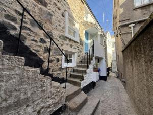 a stone alley with stairs next to a building at Sixpence Cottage, a few steps from the harbour! in St Ives