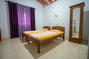 希克杜沃The Quiet House - Hikkaduwa的紫色窗帘间内的两张床