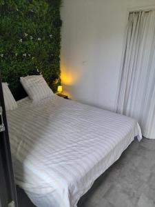 un letto bianco in una stanza con una pianta di Marina Cap Coudalère Barcarès a Le Barcarès