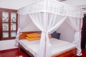 une chambre avec un lit à baldaquin dans l'établissement Red Araliya Villa Weligama, à Weligama