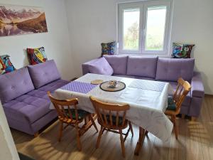 a living room with a purple couch and a table at Horizont Cemerno 