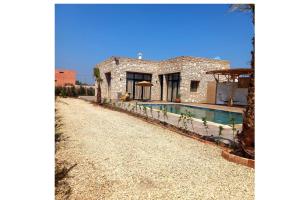 a stone house with a swimming pool in front of it at Villa avec piscine 15 minutes de l'aéroport in Essaouira