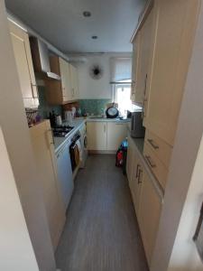 a kitchen with white cabinets and a long hallway at Burton Down Town Apartment in Burton upon Trent
