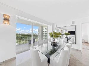 a dining room with a glass table and white chairs at Coconut Grove Elegance Five Star Condo Living in Miami