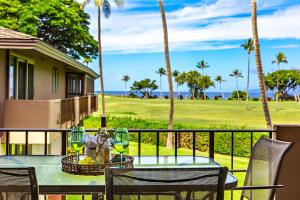 a table with wine glasses on a balcony with palm trees at Maui Eldorado Condo J206 in Kaanapali