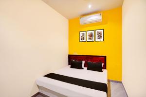 a bedroom with a bed with a yellow wall at HOTEL O S S STAY INN in Nagpur