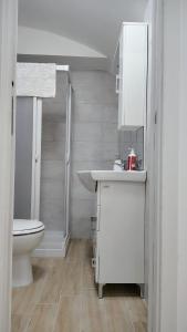 a white bathroom with a toilet and a sink at Roca House in Valenzano