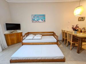 two beds in a room with a table and a television at FLAT ILHA FLAT HOTEL in Ilhabela +22 photos