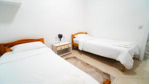 two beds in a room with white walls at Skyline Suites Belgrade in Ledine