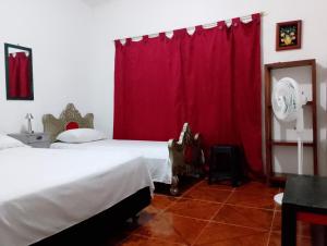 Un dormitorio con una cama y una cortina roja. en Brisas del Río, en Honda