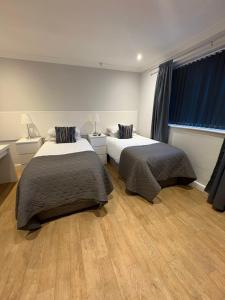 two beds in a room with wood floors and windows at Watts Lodge in Bicester