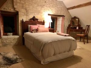 a bedroom with a large bed with pink pillows at Charming vintage cottage in Chaumussay