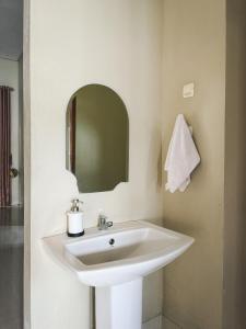Un lavabo blanco en un baño con espejo. en Villa Restu 5 Cozy 2BR Mountain View in Puncak, en Paragajen