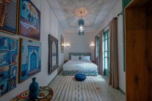 ein Schlafzimmer mit einem Bett und Gemälden an den Wänden in der Unterkunft Riad Nejma Benyoussef in Marrakesch + 105 Fotos