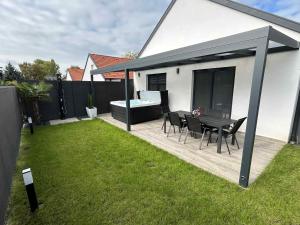 eine Terrasse mit Tisch und Stühlen in einem Hof in der Unterkunft Waikiki Apartman House with Jacuzzi in Siófok