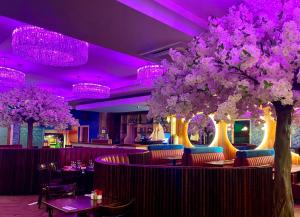a restaurant with purple lighting and trees and tables and chairs at The Talbot Hotel in Belmullet