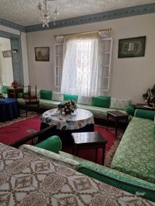 uma sala de estar com sofás verdes e uma mesa em Benaliem house em Tânger