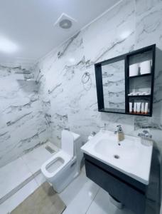 a white bathroom with a toilet and a sink at Lunar Mirage Camp in Wadi Rum