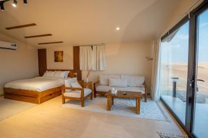 a bedroom with a bed and a couch and a table at Marbella bungalows desert private camp in Bidiyah +37 photos