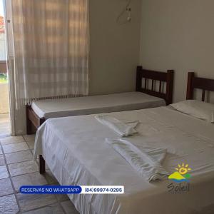 two twin beds in a bedroom with a window at Pousada Soleil de Genipabu in Contenda
