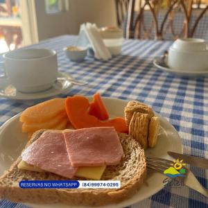 a plate of food with meat and bread on a table at Pousada Soleil de Genipabu in Contenda