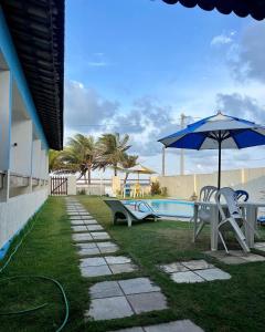a patio with a table and an umbrella and a pool at Pousada Soleil de Genipabu in Contenda