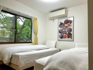 two beds in a room with a window at Arusa-Ishite 2F in Matsuyama