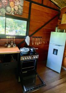a small kitchen with a stove and a refrigerator at Cabaña Río San Carlos Ecolodge in Boca Tapada