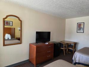 a hotel room with a television on a dresser with a mirror at Winnie Inn Suites & RV Park in Winnie