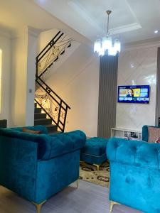 a living room with blue couches and a tv at Reagal Apartments, WMachine, WiFi, 13 mins DRV from Ikeja, OPIC ESTATE in Agege