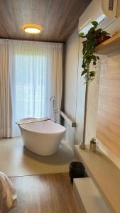 a large white tub in a bathroom with a window at Pousada Rancho na Serra in Espera Feliz