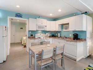 a kitchen with white cabinets and a table and chairs at Tybee Tyme Lower in Tybee Island