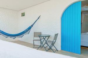 two chairs and a table in a room with a blue door at KEFI POUSADA in Maragogi +33 photos