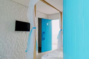 a room with a blue door and a bed and a television at KEFI POUSADA in Maragogi