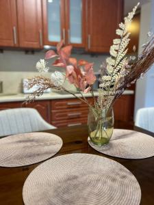 Una mesa de madera con dos platos y un jarrón con flores. en Chodorowska Home, en Świnoujście