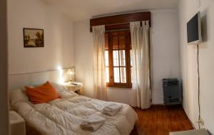 a bedroom with a bed with an orange pillow on it at Bungalows Punta Azul in Villa Carlos Paz