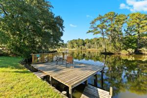 a wooden dock with a chair sitting on top of a lake at Tara's Riverfront Hideaway in Mobile