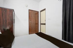 コーターにあるHotel O Shri Panchmukhi Residency Baran Roadの白いベッドと木製のドアが備わるベッドルーム1室が備わります。